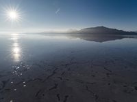 the sun shines above the horizon and water and rock formations along the shore line