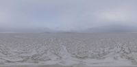 a cloudy winter day on the beach and sand and water with waves, with a distant island behind it