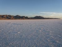 lone snow skier in the middle of flat expanse, with mountains on far side in background