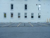 a street with a building near the building in the middle and on the left of which is a parking lot, as shown in this photo