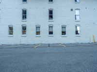 a street with a building near the building in the middle and on the left of which is a parking lot, as shown in this photo