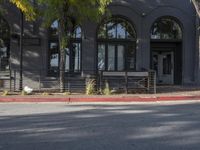 the sidewalk near the entrance to a building that is gray, with windows and fence