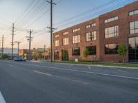 an empty street in front of a large red brick building on the other side of the road is a street light that has a line for motorists