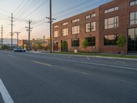 an empty street in front of a large red brick building on the other side of the road is a street light that has a line for motorists