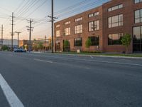 an empty street in front of a large red brick building on the other side of the road is a street light that has a line for motorists