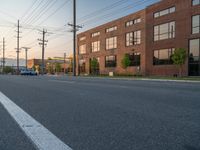 an empty street in front of a large red brick building on the other side of the road is a street light that has a line for motorists