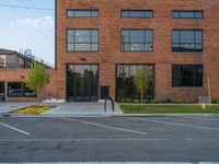 an empty street in front of a large red brick building on the other side of the road is a street light that has a line for motorists