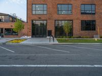 an empty street in front of a large red brick building on the other side of the road is a street light that has a line for motorists