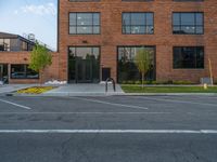 an empty street in front of a large red brick building on the other side of the road is a street light that has a line for motorists