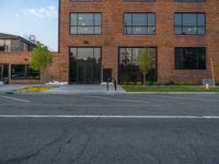 an empty street in front of a large red brick building on the other side of the road is a street light that has a line for motorists