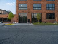 an empty street in front of a large red brick building on the other side of the road is a street light that has a line for motorists