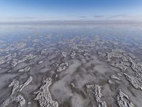 view from the airplane's side shows the water and sand that looks like water in the sky