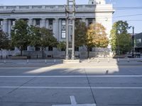 a bus and people walking around an intersection in front of a building and a statue