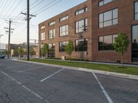 an empty street in front of a large red brick building on the other side of the road is a street light that has a line for motorists