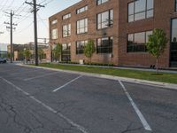 an empty street in front of a large red brick building on the other side of the road is a street light that has a line for motorists