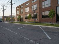 an empty street in front of a large red brick building on the other side of the road is a street light that has a line for motorists