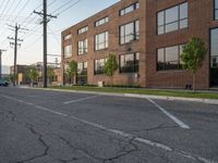 an empty street in front of a large red brick building on the other side of the road is a street light that has a line for motorists