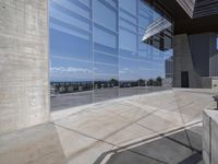 this is an outdoor patio with a glass fence next to the building and some benches