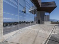 this is an outdoor patio with a glass fence next to the building and some benches