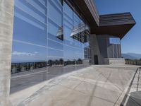 this is an outdoor patio with a glass fence next to the building and some benches