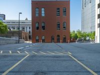 a street with a building near the building in the middle and on the left of which is a parking lot, as shown in this photo