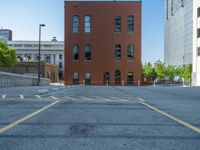 a street with a building near the building in the middle and on the left of which is a parking lot, as shown in this photo