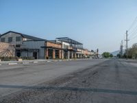 the empty street outside of the business district is empty and deserted with vehicles parked in it