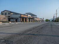 the empty street outside of the business district is empty and deserted with vehicles parked in it