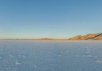 an open area with water and mountains in the background and blue sky above it's horizon