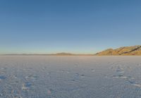 an open area with water and mountains in the background and blue sky above it's horizon