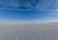 blue sky with clouds and sun in it over open space with snow covered land in foreground