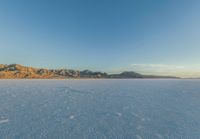 two people snowboarding across an ice - covered landscape of mountains and a vast blue sky