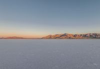 a very wide open plain with mountains in the background as seen from near a distant point