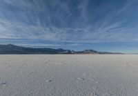 the view of snow capped mountains from a field in the distance, with tracks of footprints on the ground