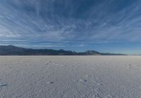 the view of snow capped mountains from a field in the distance, with tracks of footprints on the ground