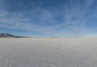 an image of a big field with some snow on it in winter time in the distance, clouds, hills and mountains are seen in the distance