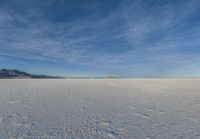 an image of a big field with some snow on it in winter time in the distance, clouds, hills and mountains are seen in the distance