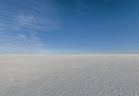 a kite flying through a blue sky over a large snow field under a clear sky