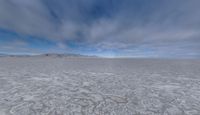 there is a very wide flat surface with snow on it's ground and mountains in the distance