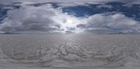 a very empty open field under cloudy skies, as seen through an angled fish eye lens