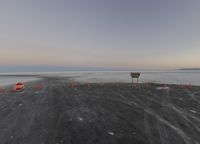 a small stop sign stands on the beach at sunset near road cones on a sand surface