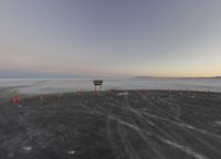 a small stop sign stands on the beach at sunset near road cones on a sand surface