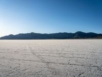 a desert with many rocky mountains in the background and water running across it from them