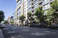 an image of cars parked on the sidewalk outside a tall building in the city on a sunny day