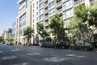 an image of cars parked on the sidewalk outside a tall building in the city on a sunny day