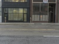a parking meter sitting in the middle of a street next to a tall building with windows