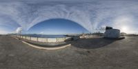 the view of some building and the ocean as seen through a fish eye lens in front of a fence