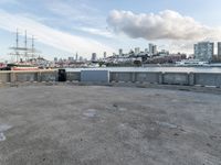 an empty parking lot with buildings and blue skies in the background with a city view