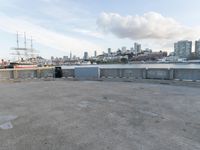 an empty parking lot with buildings and blue skies in the background with a city view