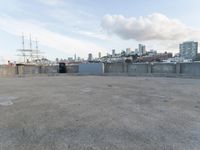 an empty parking lot with buildings and blue skies in the background with a city view